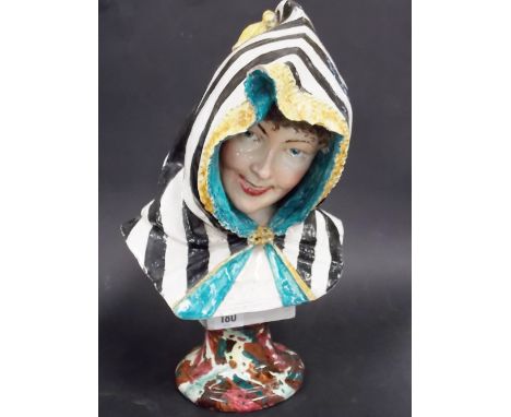 19th Century continental faience bust of a smiling lady, wearing a striped hood, upon a  circular pedestal, SM and arrow mark