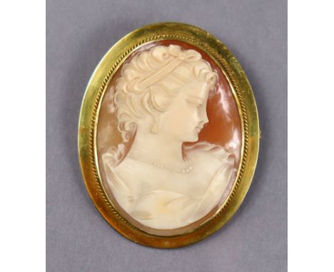 A carved shall oval cameo brooch depicting a female bust, 1¾” x 1½”, in yellow metal wide mount marked: “9ct.”; with safety c