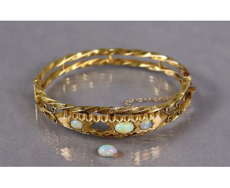 A 9ct. gold &amp; opal stiff hinged bangle of open rope-twist design, set four graduated oval stones (one stone loose) with s