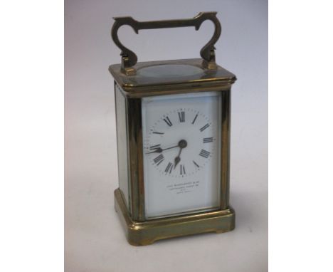 An Edwardian brass carriage clock, the enamel dial with retailers name JAS SHOOLBRED & Co, Tottenham Court Road, 15cm high (h