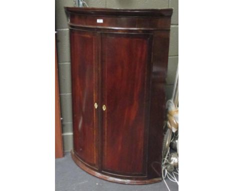 A George III mahogany bow front corner cupboard, together with a three tier cake stand  