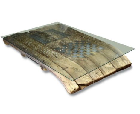 A 19th century threshing board, now mounted as a glass topped coffee table, the slatted frame inset with flints and other sto