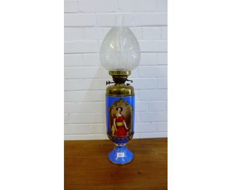 A continental porcelain oil lamp painted with a female figure panel to front to a blue ground with gilt acanthus leaf decorat