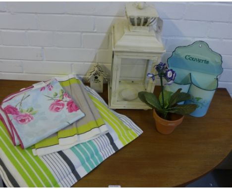 A cream painted metal lantern light, a shabby chic couverts enamel cutlery stand, a linen table runner, a striped cushion and