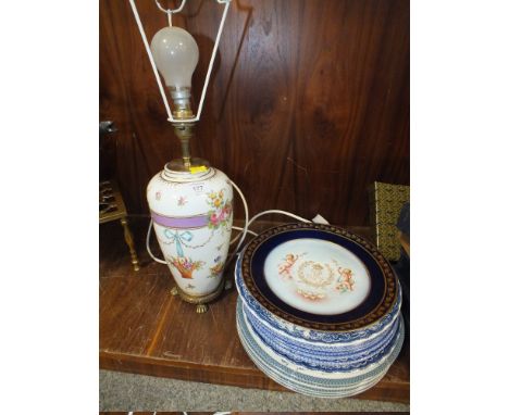 A GILT MOUNTED CERAMIC LAMP WITH FLORAL RIBBONS AND SWAG DESIGN TOGETHER WITH A SELECTION OF PLATES