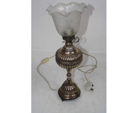 A late Victorian white metal lamp, having associated frilled glass shade above a fluted font, on domed foot (later converted)
