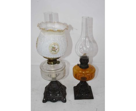 A late Victorian oil lamp having an opalescent frilled glass shade above a clear glass font on a pierced iron base, height 49