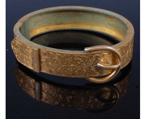 A late Victorian gilt metal 'belt' bangle, having hinged action and bright cut engraved decoration, 65mm