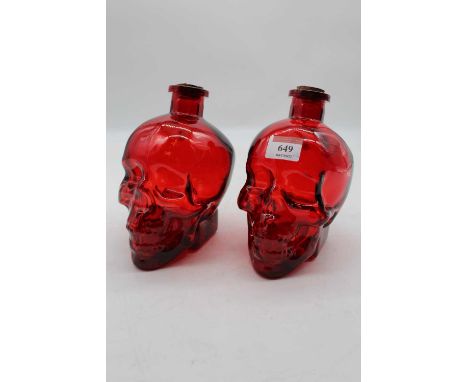 A pair of reproduction ruby tinted glass bottles, each in the form of a skull, h.17cm 