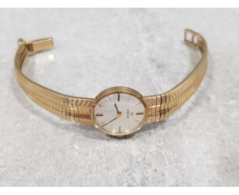 Ladies 9ct yellow gold omega watch, featuring round case set with silver dial + gold baton haw markers, manual wind complete 