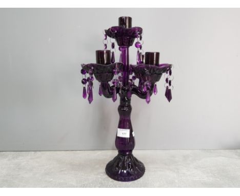 A purple moulded glass four branch candelabra with lustre drops 42cm high.