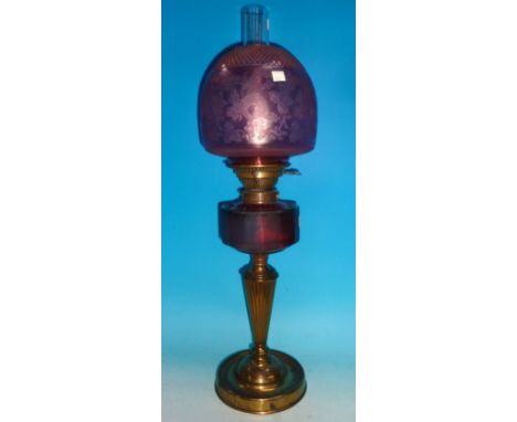 A 19th century brass oil lamp with cranberry reservoir and etched shade, on tapering reeded column and circular base