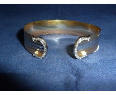 A modern ribbed yellow and white metal bangle in the style of Cartier, the 2 'C' scroll terminals each set with 17 diamonds, 