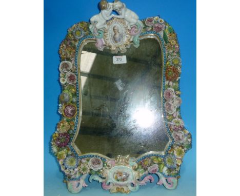 A 19th century Meissen shaped rectangular wall mirror with portrait miniature crest supported by 2 cherubs, extensive encrust