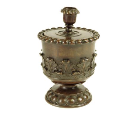  A treen tobacco jar, the lid with a candle sconce, above a beaded rim and a leaf carved body, late 19th / early 20th century