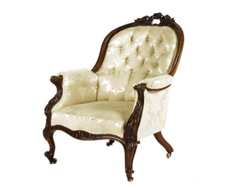  A Victorian walnut armchair, the moulded frame carved with leaves and flowers, with a button back upholstered in ivory damas