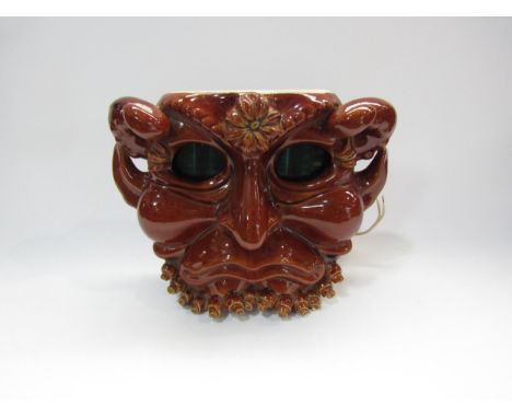 A Russian (Soviet) ceramic wall clock, ca. 1970, in the form of a grotesque horned gargoyle mask, the eyes showing the time b