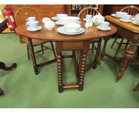 An 18th Century pegged oak gateleg table the rising leaves oval top and cutlery end drawer over bobbin turned legs joined by 