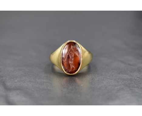 An 18ct gold carnelian intaglio ring, the oval Roman intaglio depicting an unusual version of the goddess Nike blowing a litu