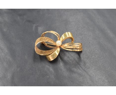 A 9ct gold ribbon bow brooch, the alternating smooth and textured ribbons set with a central cultured pearl, marked 375, 5g
