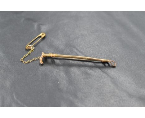 A yellow metal bar brooch stamped 9ct modelled as a riding crop, metal pin, approximately 1.7g gross