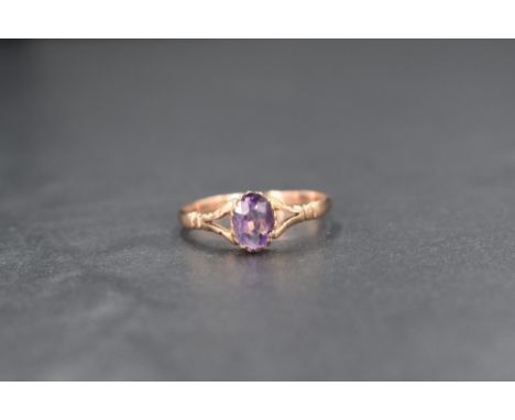 A 9ct rose gold amethyst set solitaire ring, the oval cut amethyst measuring approximately 0.75ct, in a claw setting with spl