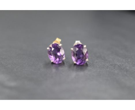 A pair of 9ct white gold amethyst stud earrings, having oval amethysts each measuring approximately 1.5ct in 4 claw basket mo
