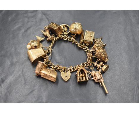 A 9ct gold curb link charm bracelet, having a padlock clasp and fifteen large charms including opening safe, chest containing