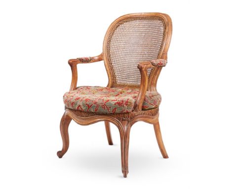 A LOUIS XV FRUITWOOD OPEN ARMCHAIR  CIRCA 1770  The caned back and seat upholstered with 19th century loop stitch carpet  99c