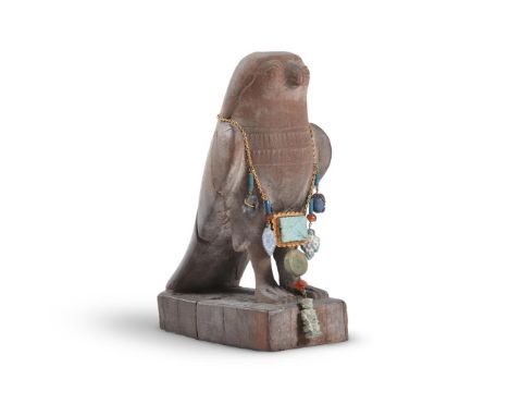 AN EGYPTIAN STYLE CARVED WOOD FIGURE OF HORUS AS A FALCON  20TH CENTURY  17.5cm high   Together with a restrung Egyptian amul