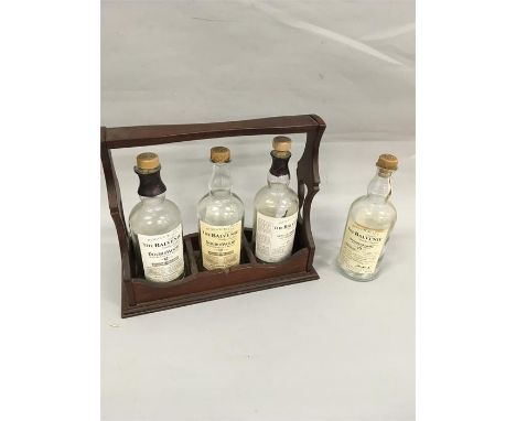 A tantalus containing three vintage whisky bottles with another bottle separate.
