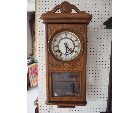 A 1930s carved oak cased wall clock with eight-day striking movement, 21" high 