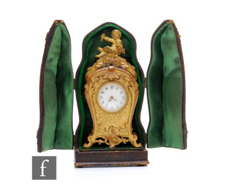 A late 19th Century French miniature travelling gilt metal mantel clock, the scrolling feet rising to a central circular whit