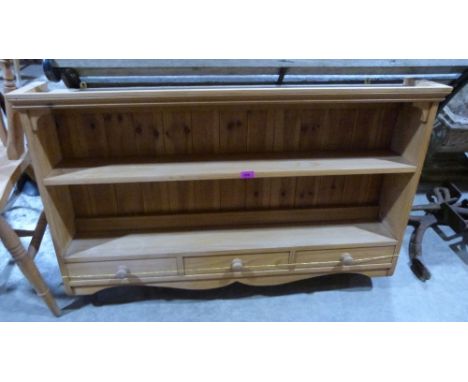 A pine hanging wall shelf with three drawers and shaped apron. 46'' wide