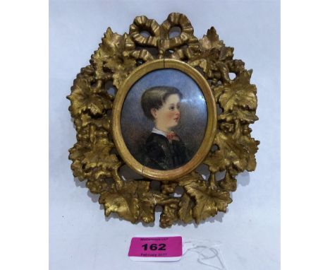 A 19th century portrait miniature of a young boy in a Florentine carved giltwood frame. 7'' high overall