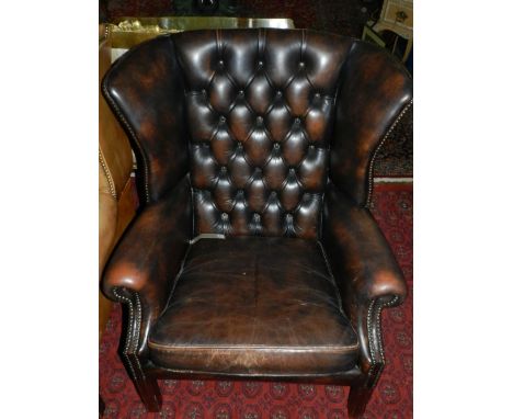 A 19th century brown leather wing back armchair, having button back upholstery, raised on square tapered legs. 
