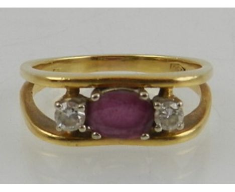A yellow metal, diamond, and ruby ring, the openwork angular mount set with an oval cut ruby, flanked by two round cut diamon