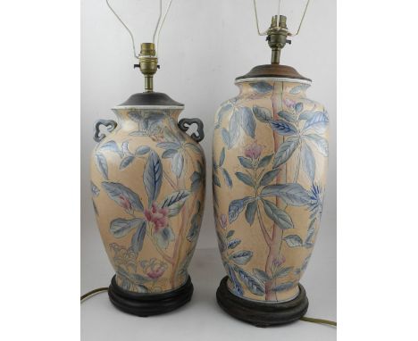 An ovoid ceramic lamp, decorated with flowers on a peach ground, raised on a wooden base, together with a similar peach groun