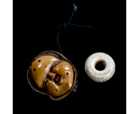 A Japanese relief carved nut netsuke, in the form of a face, Meiji Period, signed, length 3.5cm, and a small ivory disc-shape