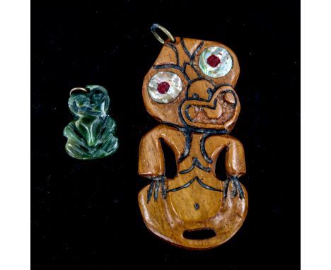 A New Zealand carved wood and mother-of-pearl inlaid tiki, length 8cm, and a small greenstone tiki, length 3cm (2) 