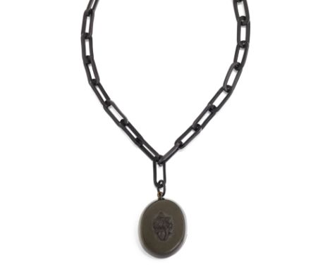 A VICTORIAN JET PENDANT AND CHAIN, the oval jet locket with carved floral decoration to front, with glazed keepsake panel to 