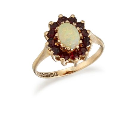 A 9 CARAT GOLD OPAL AND GARNET CLUSTER RING, the oval opal cabochon surrounded by small round garnets, all set in 9ct gold wi