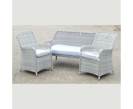 A grey rattan sofa, 120cm, together with two armchairs with cushions