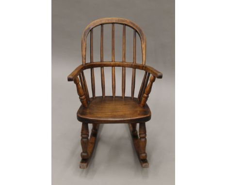 A Victorian elm child's stick back open arm rocking chair. 