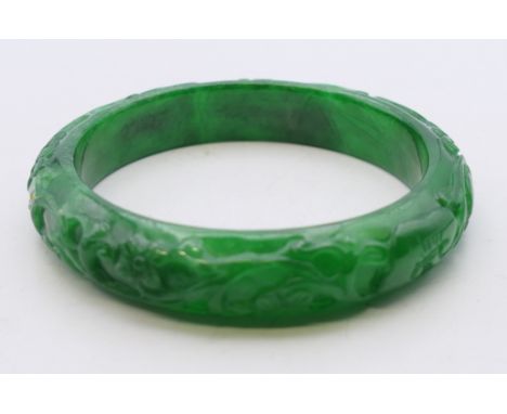A carved apple green jade bangle. Approximately 5.5 cm internal diameter. 