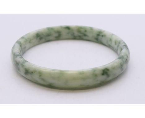 A two-tone speckled jade bangle. Approximately 6 cm internal diameter. 