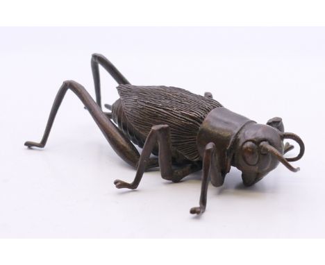 A bronze articulated model of a locust. 7.5 cm long.