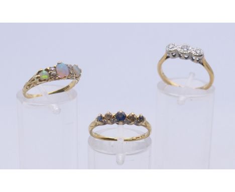 An 18 ct gold opal and diamond ring and two further diamond set 18 ct gold rings. The former ring size K. 7.2 grammes total w