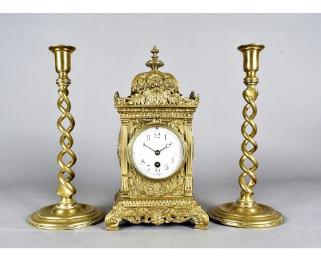 A large brass mantle clock, having white face with black Arabic numerals, the body having raised swag and floral design, with