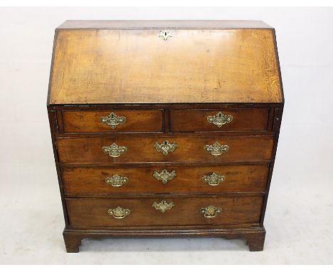 A George III oak bureau, having two short over three graduated long drawers under fall front to fitted interior, bracket feet